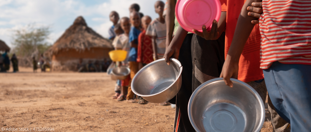 Kinder stehen hintereinander in einer Reihe und halten leere Schalen in den Händen