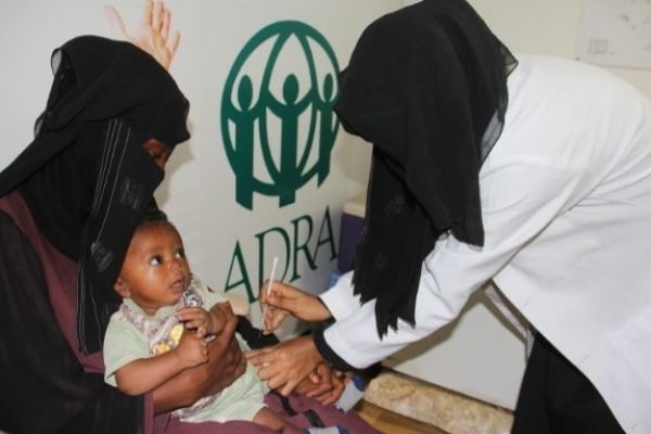 Ein Kind in den Armen seiner Mutter erhält eine Spritze von einer Ärztin