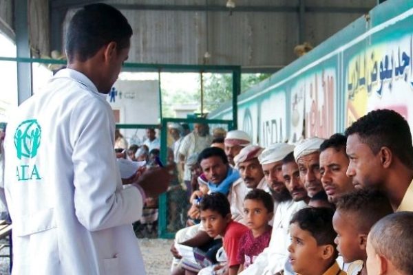 Ein Arzt steht vor einer Gruppe Männern und Kindern