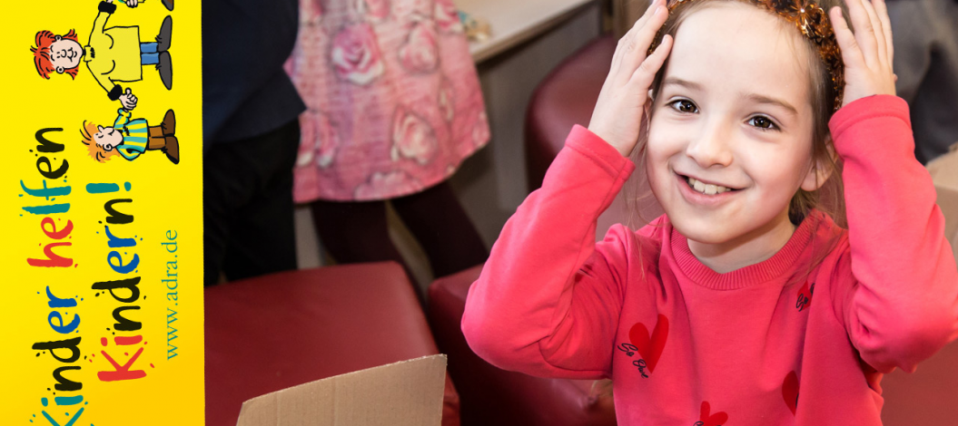 Mädchen schaut lächelnd mit Blumenkrone in die Kamera