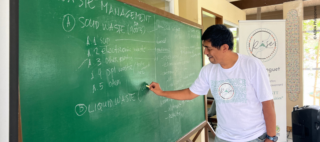 Lokaler Trainer erklärt Abfallmanagement an Tafel bei ADRA-Schulung in Benguet, Philippinen, zu Katastrophenvorsorge und Klimaanpassung