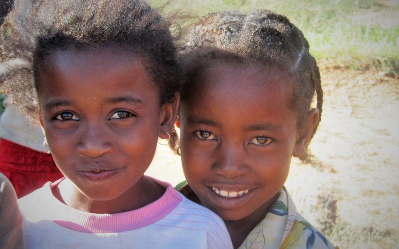 Zwei junge Mädchen schauen mit großen, strahlenden Augen in die Kamera, während eines der Mädchen lächelt