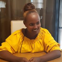 Nanati sitzt an einem Tisch und lächelt