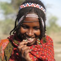 Eine nach unten schauende lachende Frau, hält ihre Hand in Richtung Mund