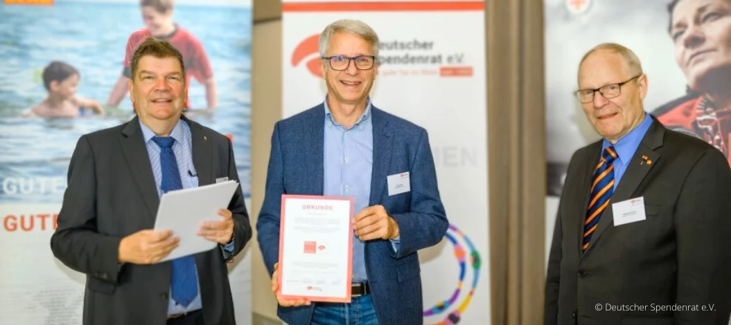 Christian Molke, Vorstandsvorsitzender von ADRA Deutschland e.V. (Mitte) nimmt die Urkunde mit dem Spendenzertifikat von Martin Wulff, Geschäftsführer (links) und Wolfgang Stückemann, Ehrenvorsitzender des Deutschen Spendenrates (rechts), entgegen. (Foto: Deutscher Spendenrat e.V.)