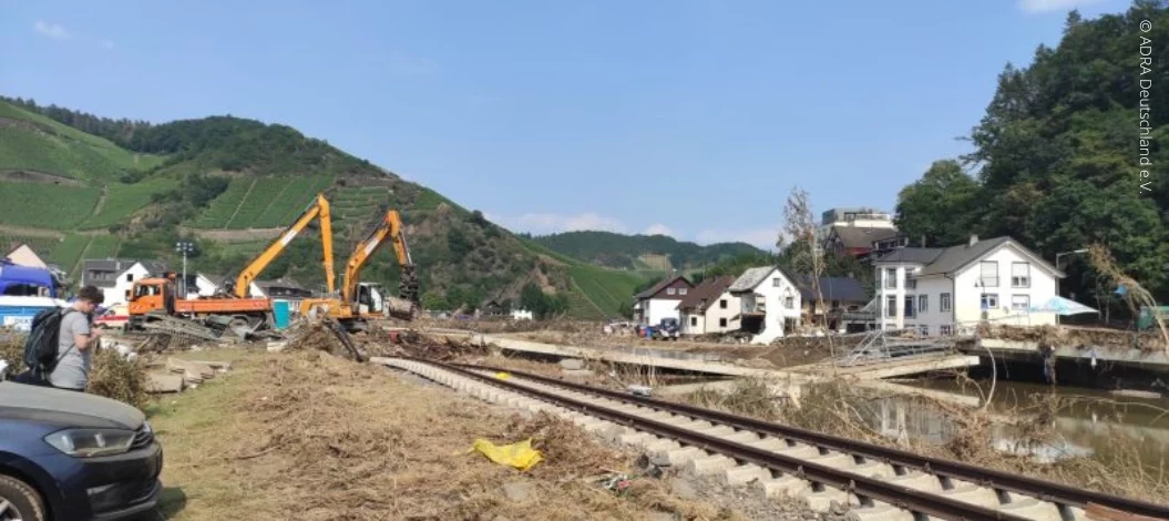 Katastrophenhilfe Hochwasser Deutschland - Bagger räumen Trümmer an einer zerstörten Brücke neben Bahngleisen in einem von Hochwasser betroffenen Tal