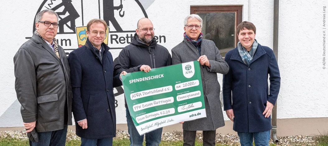 Christian Molke von ADRA Deutschland übergibt Spendenscheck über 20.000 Euro an Feuerwehrkommandant Timo Bablok, umringt von drei Kollegen.