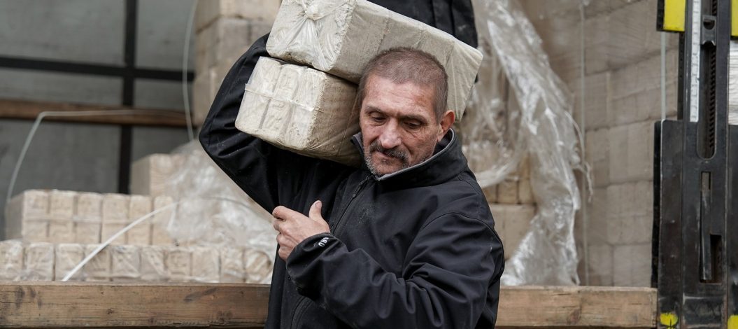 Ein Mann trägt gepresste Brennstoffblöcke von einem Lkw, die im Rahmen der ADRA-Winterhilfe in der Ukraine verteilt werden.