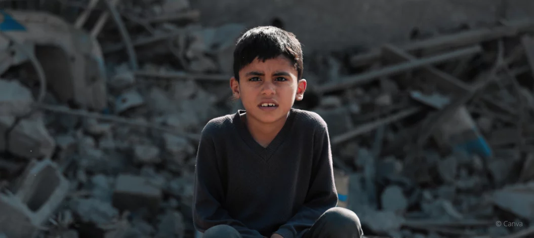 Ein Junge sitzt mit ernstem Blick vor zerstörten Gebäudetrümmern, Symbol für die Not und Unsicherheit in Krisengebieten