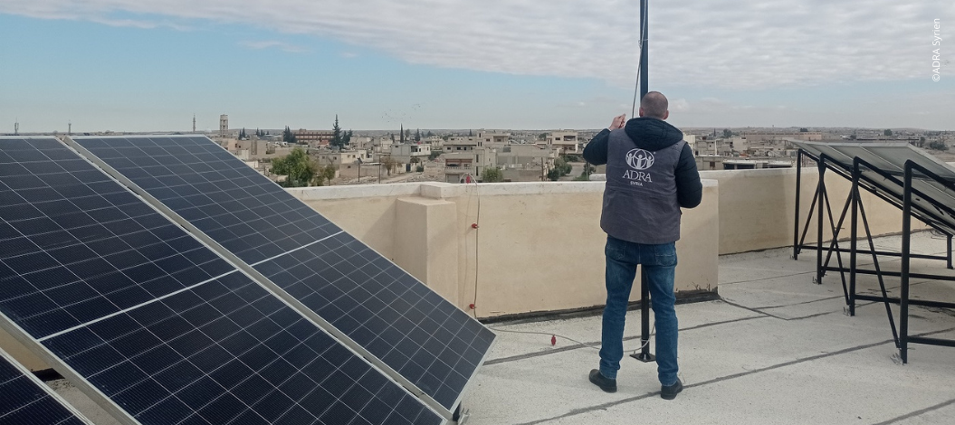 ADRA-Mitarbeiter installiert Solarpanels auf Dach in Syrien – nachhaltige Stromversorgung für Flüchtlingsunterkünfte